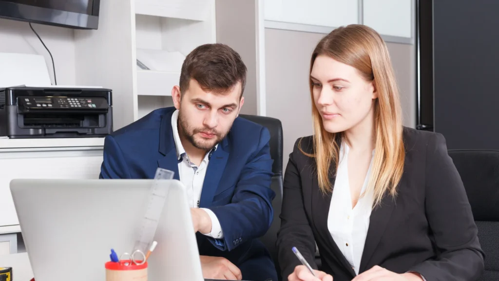 Un homme et une femme travaillant devant un ordinateur, expliquant les différences entre apporteur d'affaires et agent commercial