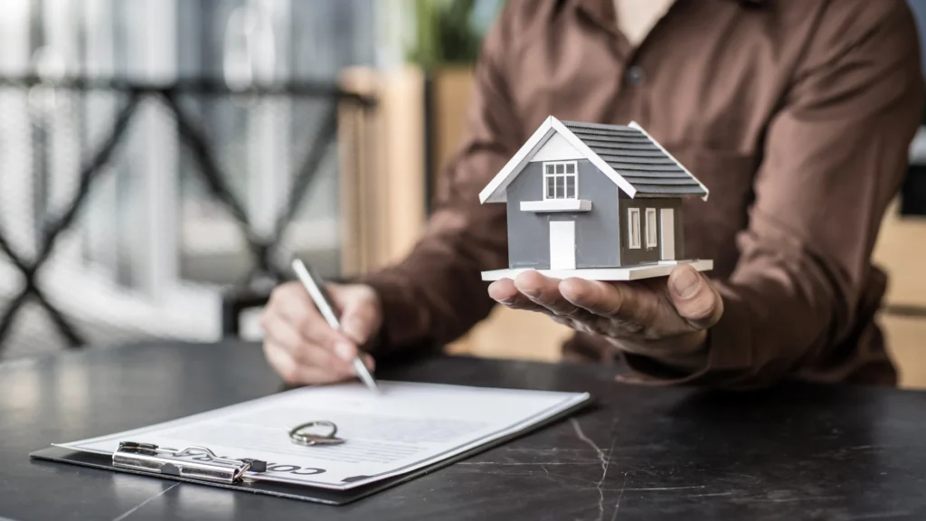 Un apporteur d'affaires en déménagement tenant une maison miniature
