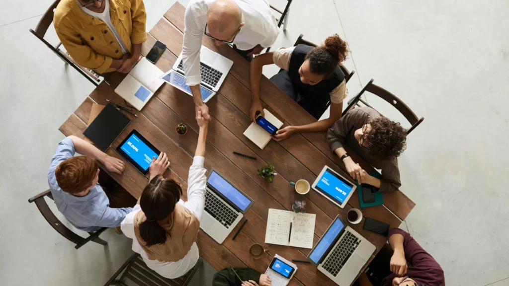 des professionnels autour d'une table se serrant la main, cela montre la stratégie de recrutement d'un apporteur d'affaires.